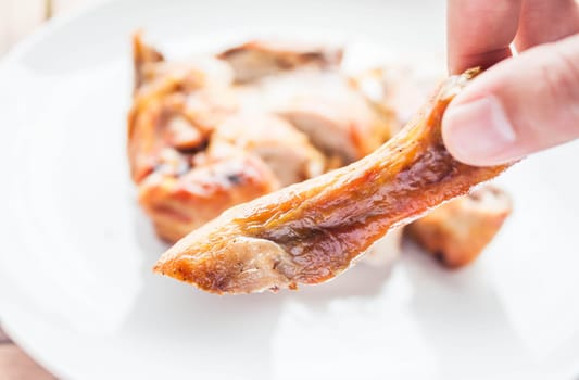 Hand on grilled chicken leg, stock photo