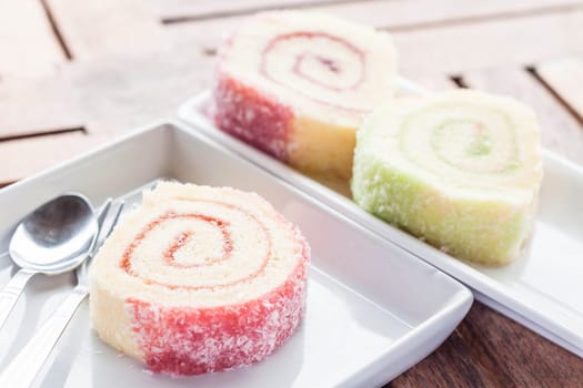 Colorful jam rolls on white dish with spoon and fork, stock photo