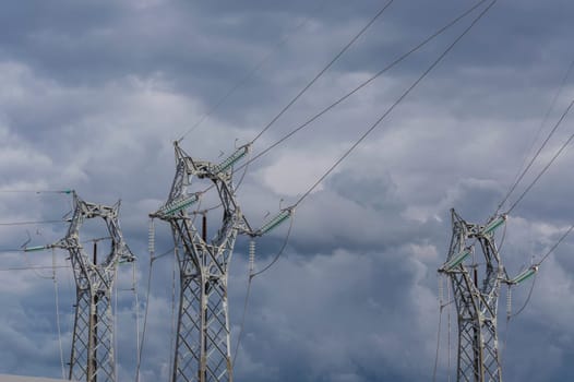 three electrical pylons on the background of a stormy sky