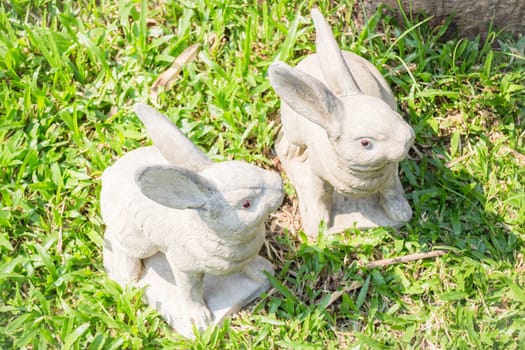 Twin rabbits of plaster decorated in green grass, stock photo