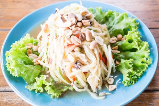 Spicy papaya salad serving on wood table, stock photo