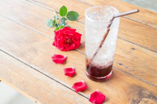 Red rose and cold pomegranate drink on wood table, stock photo