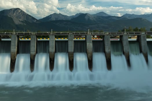Wide time exposure of the spillway on the Kananaskis hydroelectric dam on the Bow River, with Canadian Rockies in the background in Alberta, Canada