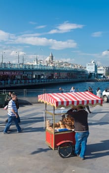 street vendor selling food in istanbul with the Galata bridge in the background. Eating on the street is part of local life here