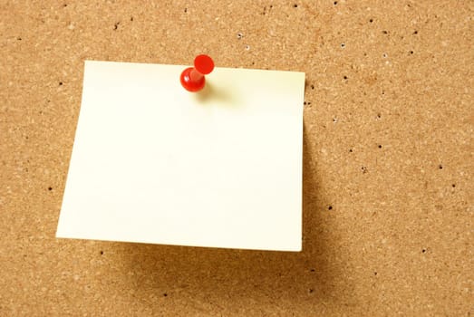 A blank note is pinned to a corkboard.