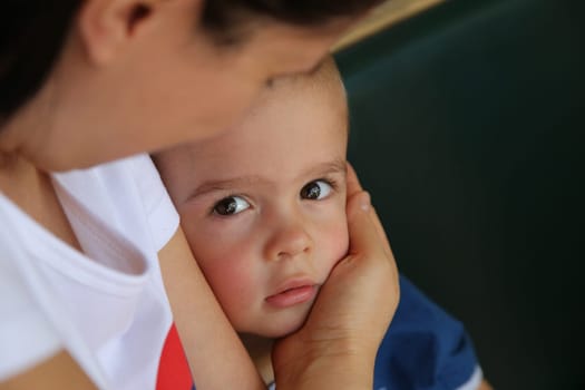 Cute little boy looking intently, with mother lovingly holding him