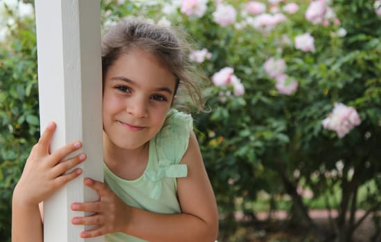 Beautiful little girl smiling and hugging a gazebo pole