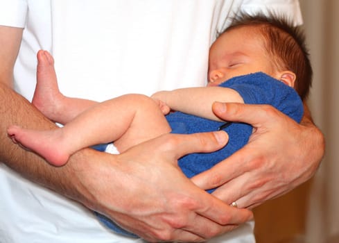 baby boy sleeping peacefully in daddy's arms