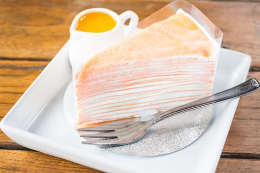 Delicious orange crepe cake serving on the plate, stock photo