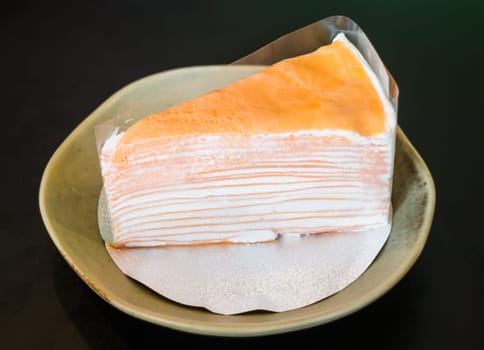 Orange whipped cream crepe cake on black background, stock photo