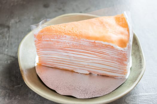Piece of homemade orange crepe cake, stock photo