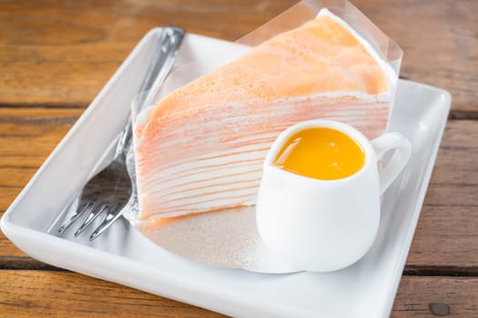 Homemade orange crepe cake serving on the plate, stock photo