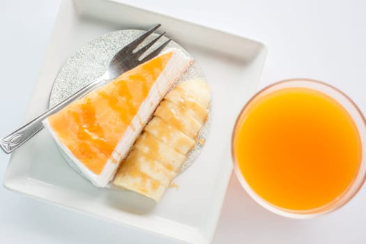 Top view of banana caramel crepe cake and orange juice on white background, stock photo