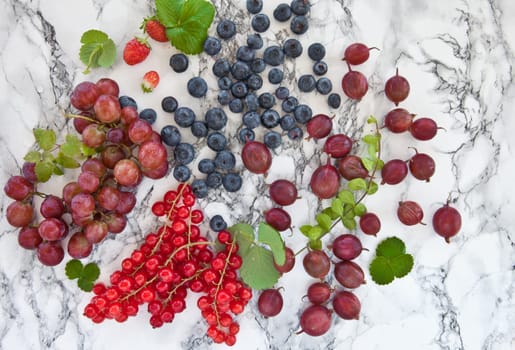 Various fresh summer berries on marble slab