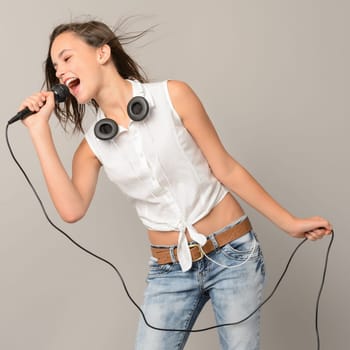 Singing teenage girl with microphone karaoke music on gray background
