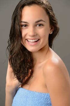 Teenage girl touch wet hair care smiling brunette on gray background