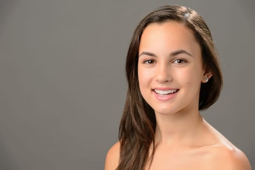 Smiling teenage girl skin care beauty brunette portrait on gray background