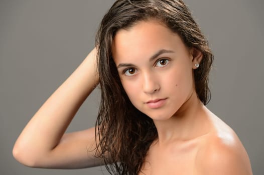 Teenage girl brunette wet hair beauty skin on gray background
