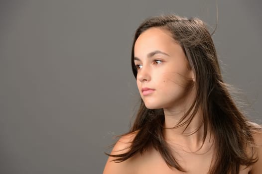 Teenage girl hair beauty skin looking away on gray background