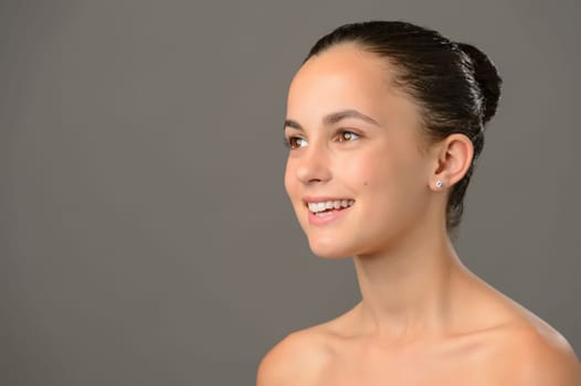 Teenage girl bare shoulders skin cosmetics beauty smiling on gray background