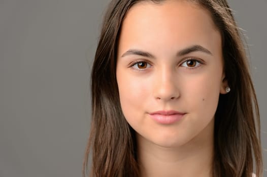 Teenage girl beauty face cosmetics brunette close-up on gray