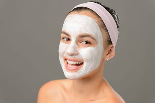 Smiling young girl face mask bare shoulders on gray background