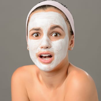 Surprised teenage girl looking camera face mask on gray background