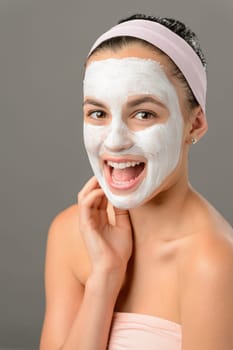 Teenage beauty smiling girl white facial mask on gray background