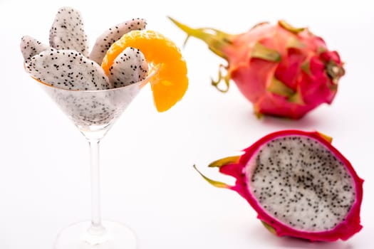 The juicy pulp of the Pitahaya blanca presented in a glass and decorated with a mandarine slice. This exotic fruit is also called strawberry pear,nanettika fruit or pitaya..