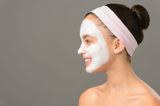 Teenage girl cosmetics mask beauty looking away on gray background