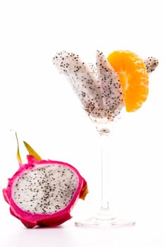 Wedges of the pitaya presented in a cocktail glass. A mandarin slice added for decoration. Next to it reads a halved pitaya..