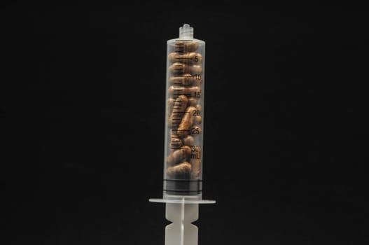 Medical Syringe Full of Pill Drugs on a Black Background
