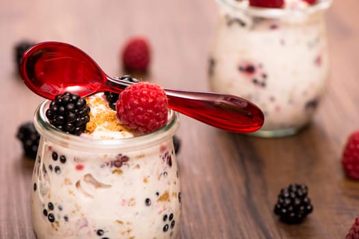 Yoghurt with fruit in the glass and red spoon