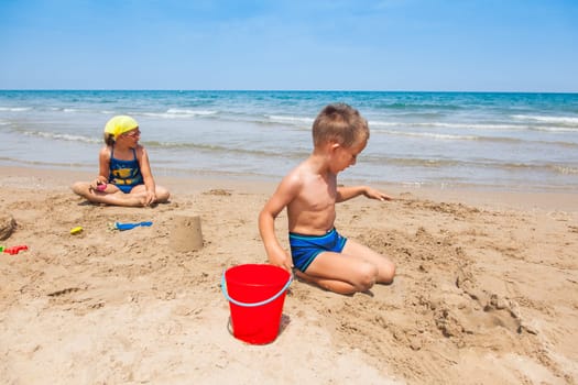 Kids playing on the beach and building sandcastle