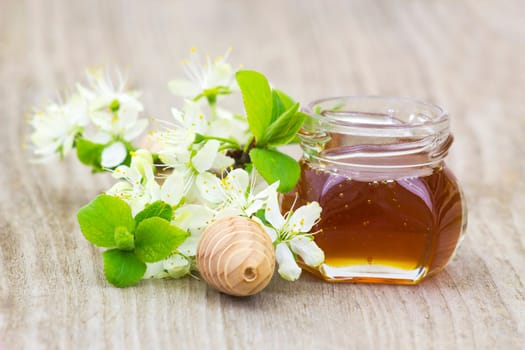 Honey in a jar, flowers and honey dipper on wooden background