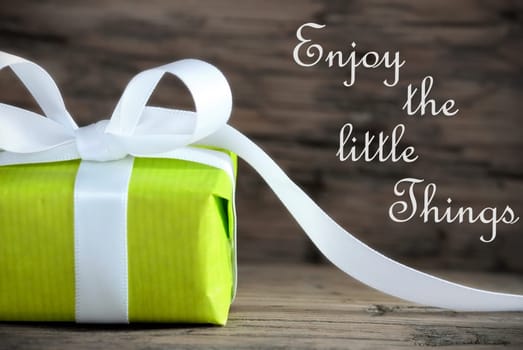 Green Gift with the Saying Enjoy the Little Things on wooden Background