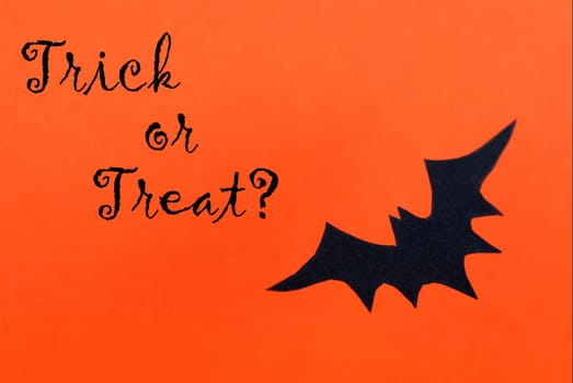 An Orange Halloween Background with a Black Bat and the Words Trick or Treat