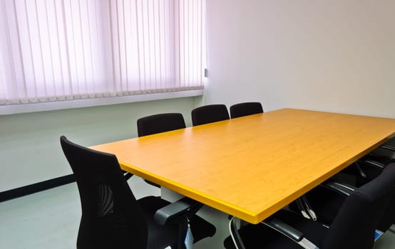 Small meeting room with wooden table and black chairs