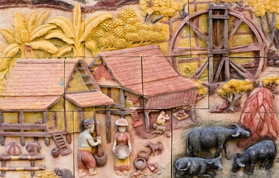 Stone carving of traditional Thai rural culture on temple wall
