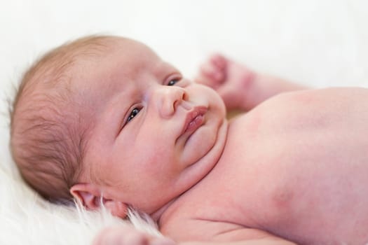 Little baby toddler newborn naked on a white fur as Detal