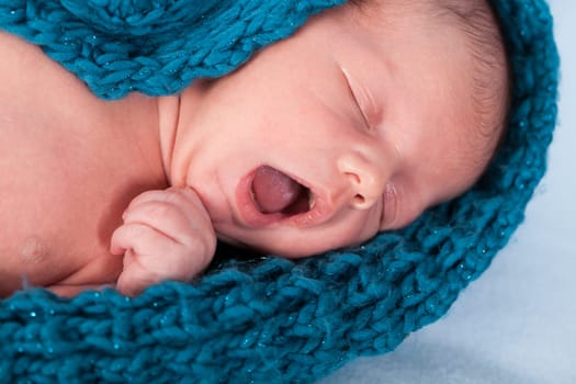Newborn baby wrapped in a scarf sleeps naked as a close-up