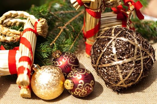 Decoration for Christmas with red and gold Christmas tree balls in front of green fir branches in the background
