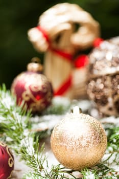 golden Christmas tree balls glittering on tannin branches with snow as macro detail