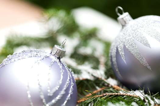 Silver Christmas tree balls in green fir branches with white shiny snow as macro detail