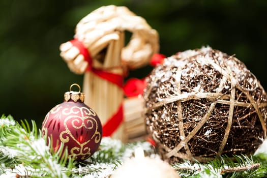 Decoration for Christmas with red and gold Christmas tree balls in front of green fir branches in the background