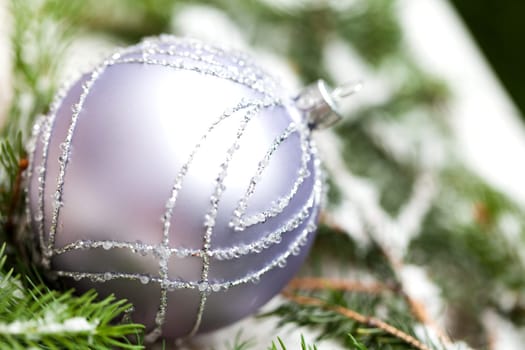 Silver Christmas tree balls in green fir branches with white shiny snow as macro detail