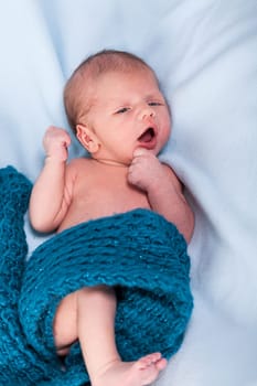 Newborn baby wrapped in a scarf sleeps naked as a close-up