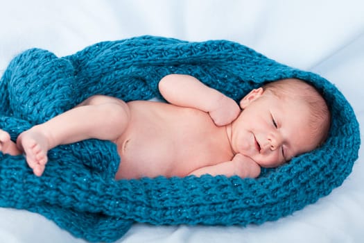 Newborn baby wrapped in a scarf sleeps naked as a close-up