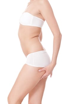 Body of attractive young woman with white underwear pinches herself in the problem areas isinted before white