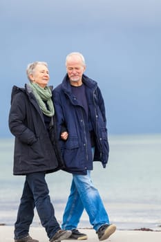 older adult happy couple walks on the beach in autumn lifestyle happiness